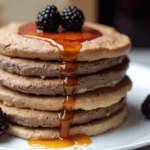 A stack of healthy banana oatmeal pancakes on a plate, topped with fresh berries and drizzled with maple syrup. Perfect for a wholesome breakfast.
