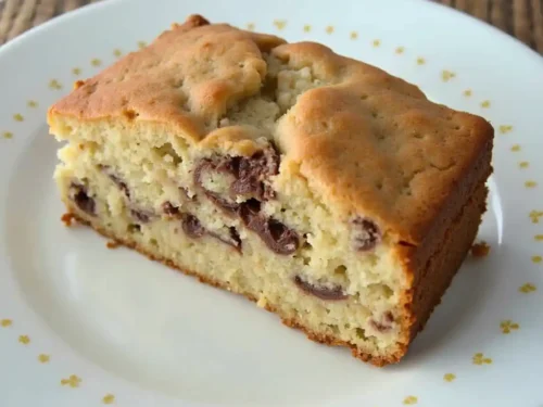 Moist banana chocolate chip cake topped with melted chocolate chips, perfect for dessert or a sweet snack.