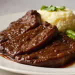 Slow Cooked Beef Cheeks Recipe 2 Tender beef cheeks served with creamy mashed potatoes and steamed green beans, garnished with fresh parsley.