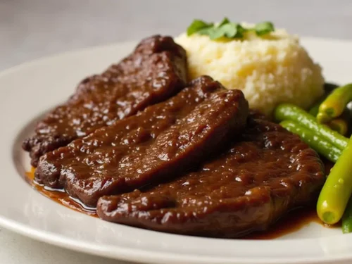 Tender beef cheeks served with creamy mashed potatoes and steamed green beans, garnished with fresh parsley.